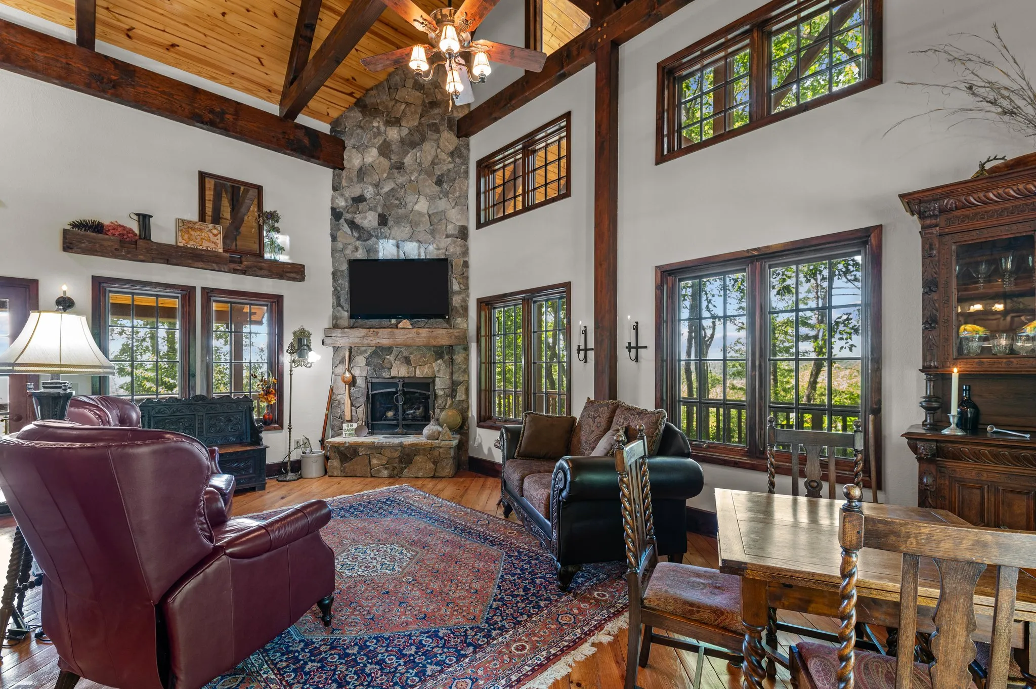 Spacious living room with soaring wood ceilings, fireplace, leather seating, and natural light