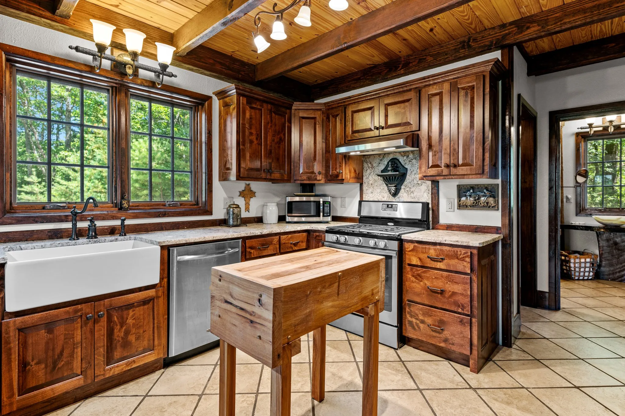 Modern kitchen with rustic wood cabinets, apron sink, stainless appliances, and island workspace