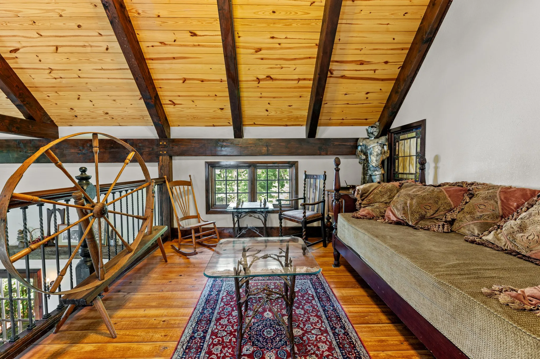 Charming loft sleeping area with decorative wooden wheel, antique furnishings, and rustic decor