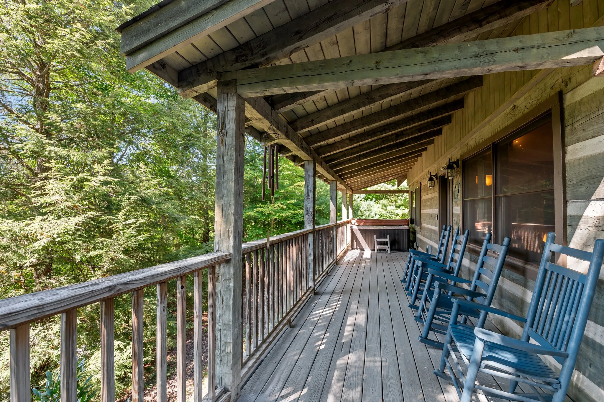 Covered Front Porch Spacious covered porch with blue rocking chairs, dining table, and forest views