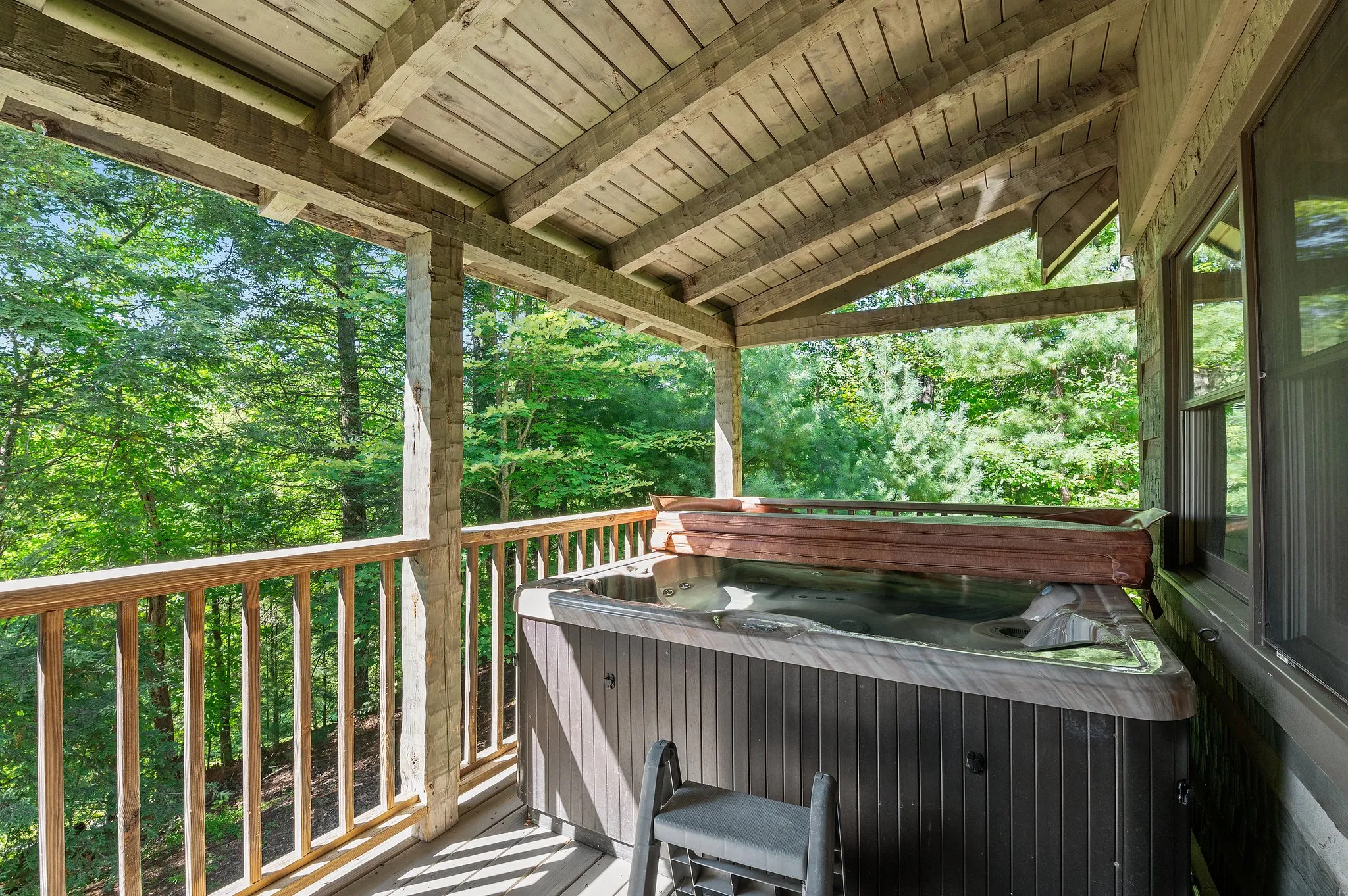 Deck Hot Tub Hot tub on covered deck with timber beam ceiling surrounded by forest greenery