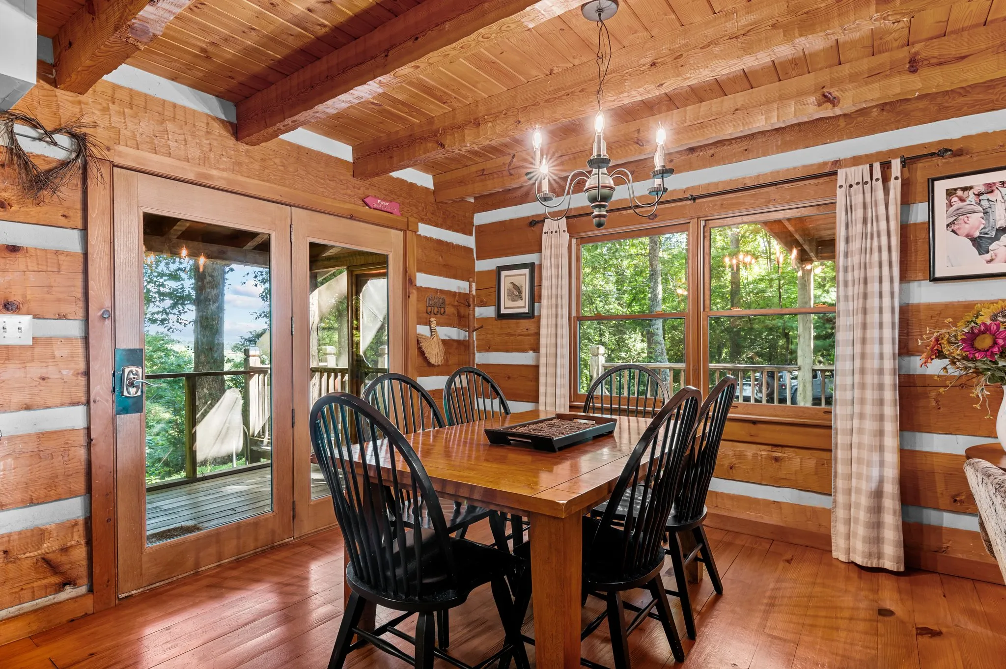 Dining Room Dining room with rustic log walls, Windsor chairs, chandelier, and glass doors to deck