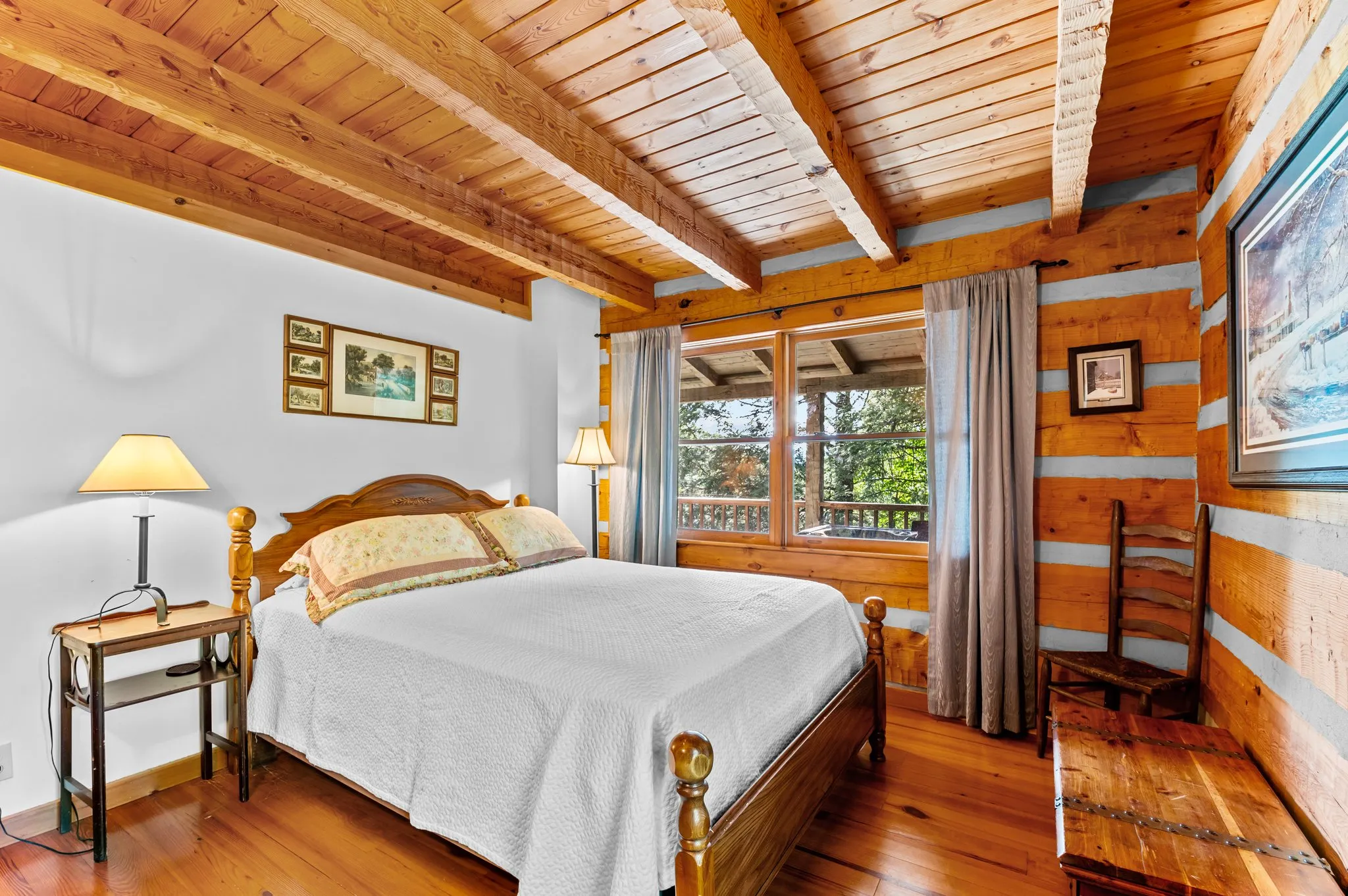 Main Bedroom Cozy bedroom with vaulted wood ceiling, iron bed frame, hardwood floors, and forest views