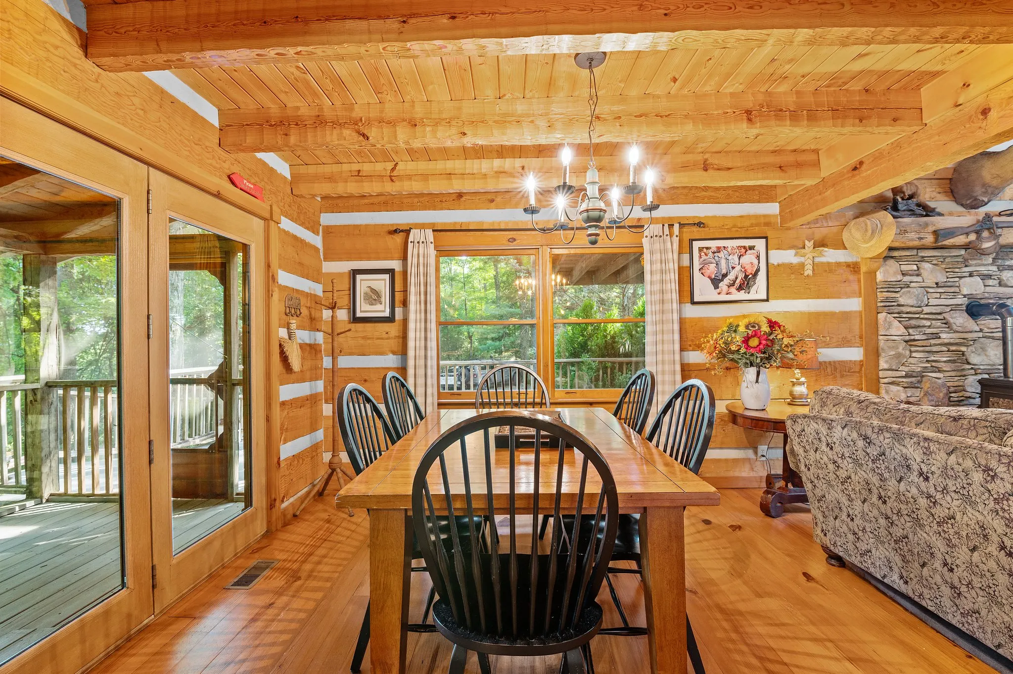 Main Dining Area Main level dining area with log walls, stone fireplace accent, and glass doors to deck