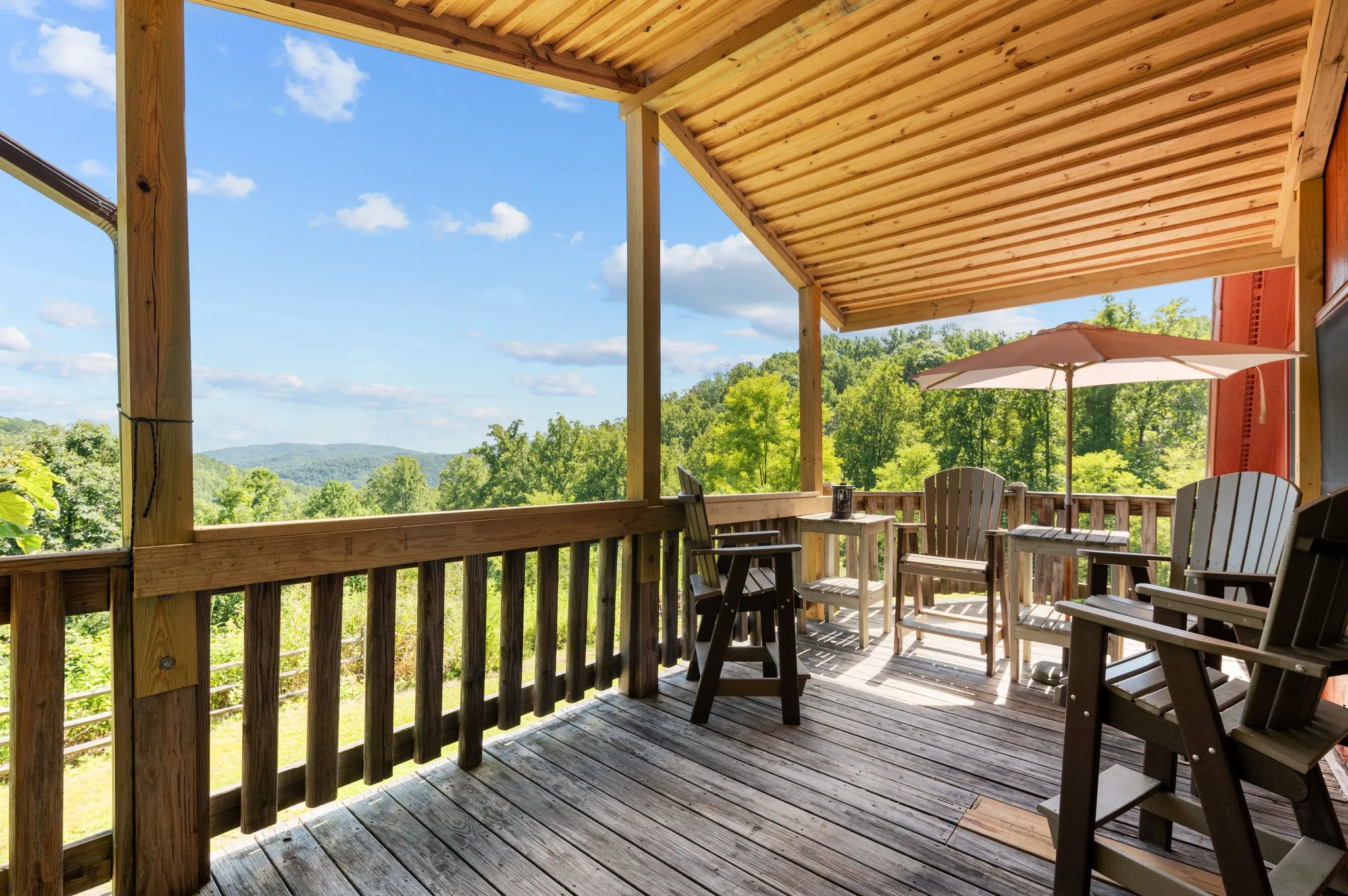 Spacious covered deck with Adirondack chairs, grill, and panoramic mountain valley views