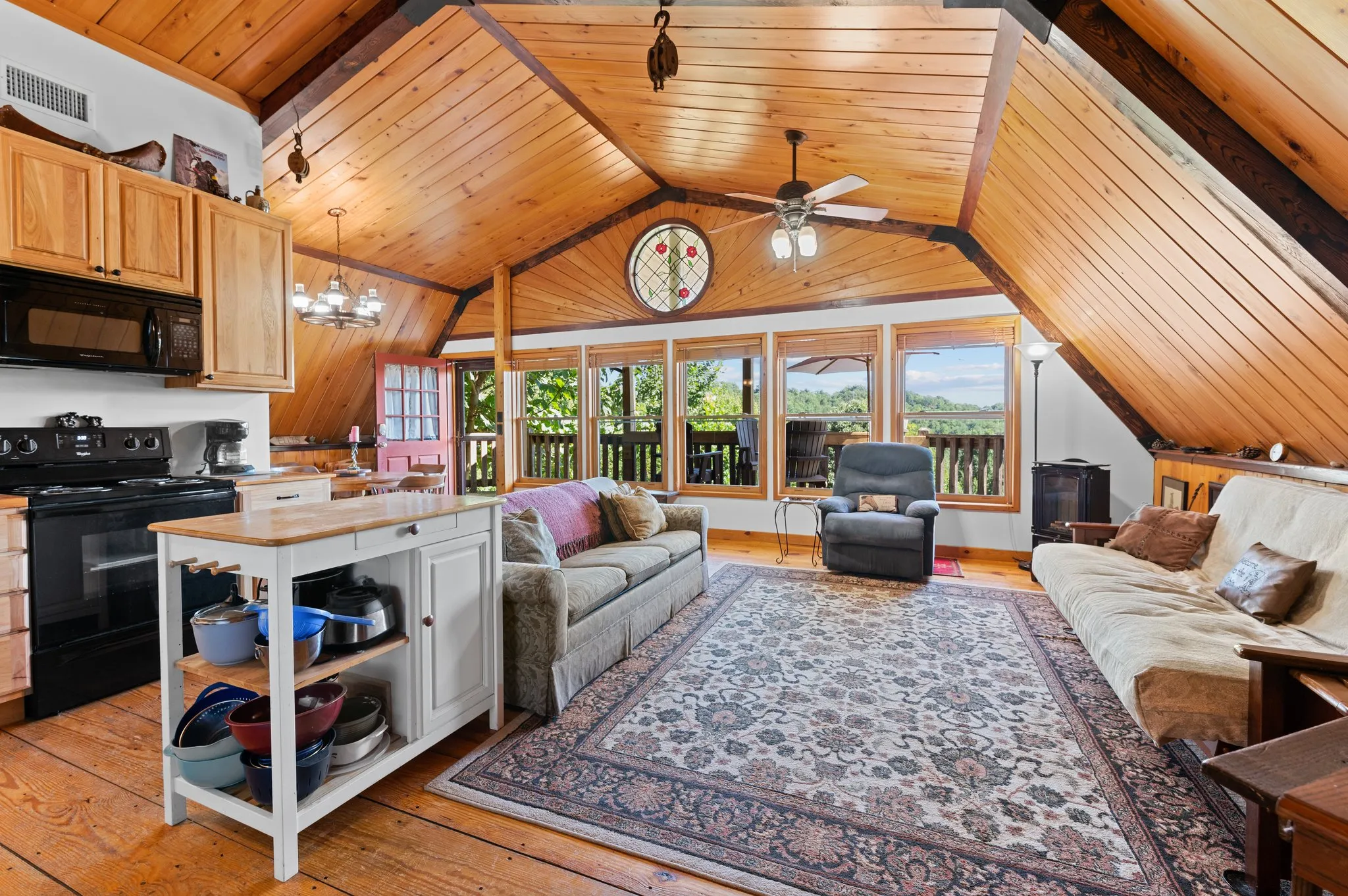 Open concept living area with vaulted wood ceiling, kitchen, seating area, and mountain views through large windows